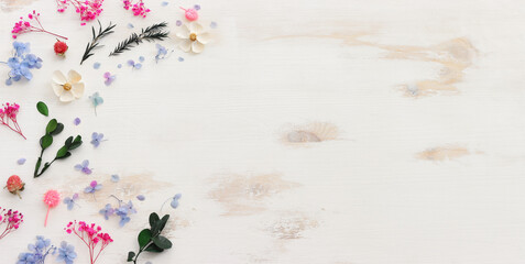 Top view image of pink, white, green and blue flowers composition over white wooden background .Flat lay