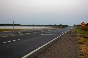 morning thick autumn fog in the fields along the highway at dawn