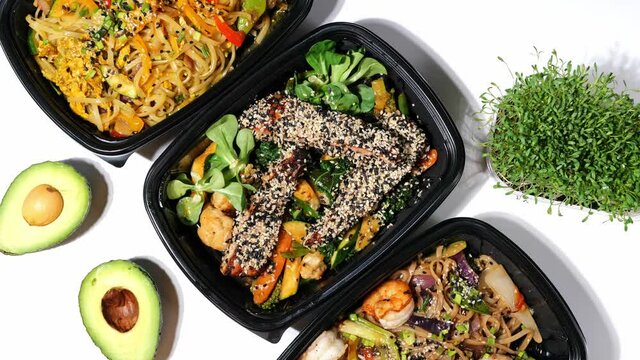Assorted Chinese food set served in take away boxes, noodles, peking duck and fry chicken, salmon, shrimps with vegetables, green peas, sauces, avocado, micro greens. Famous vietnamese Asian food dish