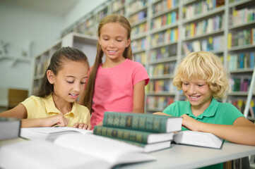 Fototapeta na wymiar Three cute classmates studying together at a public library
