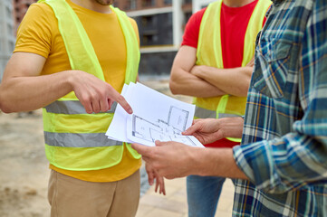 Three adult men discussing a new house plan outdoors