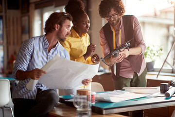 beardy caucasian guy presenting drone as a solution for filming an advertisement to his male boss and afro-american female colleague