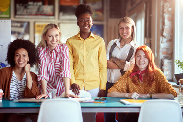 group of young working women posing for a photo portrait, looking at camera.