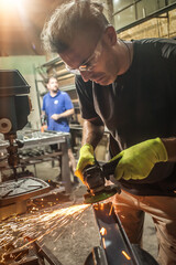Two craftsman with electric grinder on steel structure in factory
