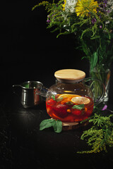 Mint tea with fruit. Atmospheric teapot on a black background