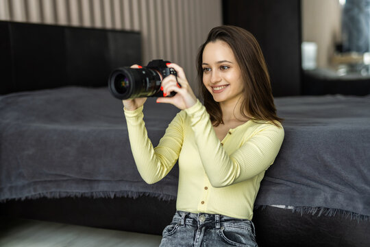 Young woman photographer holding camera for choose photograph in while looking at it.