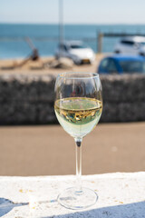 Glass of white wine served on outdoor terrase with seaview, summer vacation