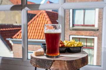 Drinking dark beer with fried cod fish fillet and french fried potatoed chips with view on street in old Zierikzee town, Zeeland, Netherland