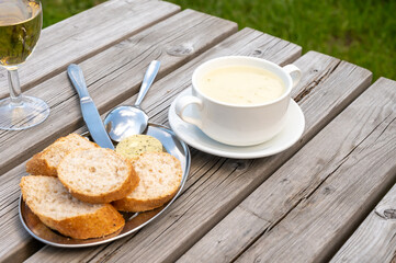 Lunch with homemade white asparagus soup and Dutch white wine served outdoor on green meadow with vineyard, asparagus and wine production farm in Netherlands