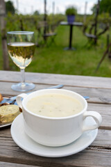 Lunch with homemade white asparagus soup and Dutch white wine served outdoor on green meadow with vineyard, asparagus and wine production farm in Netherlands