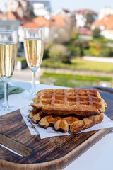 Breakfast with fresh baked belgian waffles and brut champagne sparkling wine in flute glasses served on outdoor bistro terrace in France