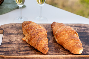 Breakfast with fresh baked croissants and  brut champagne sparkling wine in flute glasses served on outdoor bistro terrace in France