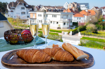 Breakfast with fresh baked croissants and  brut champagne sparkling wine in flute glasses served on outdoor bistro terrace in France