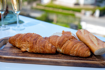 Breakfast with fresh baked croissants and  brut champagne sparkling wine in flute glasses served on outdoor bistro terrace in France