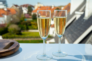 Drinking of brut champagne sparkling wine in flute glasses on outdoor bistro terrace in France