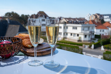 Drinking of brut champagne sparkling wine in flute glasses on outdoor bistro terrace in France