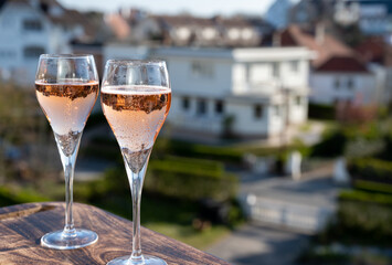 Drinking of rose champagne sparkling wine from flute glasses on outdoor terrace in France - obrazy, fototapety, plakaty