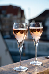 Drinking of rose champagne sparkling wine from flute glasses on outdoor terrace in France