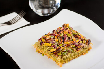 Kadayif dessert with pistachio on a white porcelain plate.