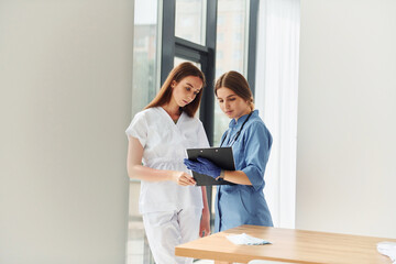 Two doctors in uniform standing indoors and working together