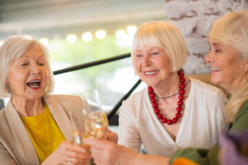 Three mature women having a celebration and drinking champaigne