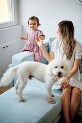 Young beautiful mother playing with her beloved baby girl at home.