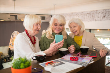 Women looking excited while watching something on a smartphone