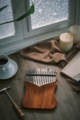 Kalimba on a wooden table by the window. It's snowing outside, relaxing and playing the Kalimba. Traditional african musical instrument. Music concept