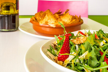 Arugula salad with parmesan cheese with walnuts and pieces of strawberries in vegan restaurant