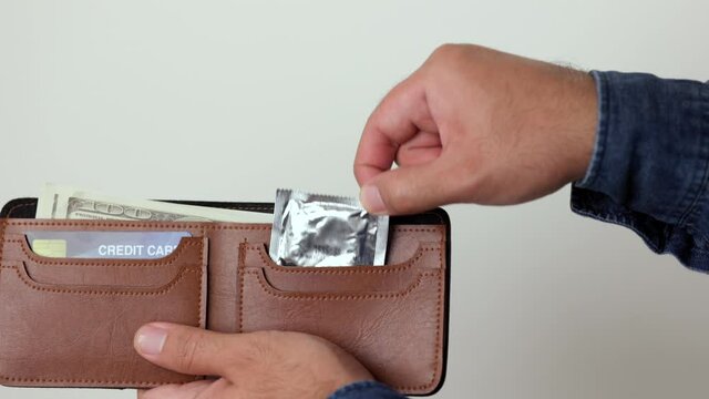 The young man took out a condom from his wallet, ready to use anytime anywhere. Campaign for safe sex and contraception.