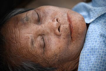 The wrinkled face of an old Asian woman sleeps alone at home alone