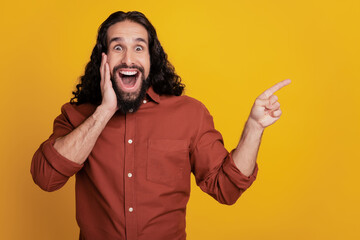 Portrait of crazy promoter guy hand cheek direct finger empty space on yellow background