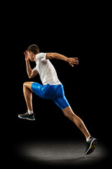 Static portrait muscular, sportive man, male athlete, runner training isolated on dark studio background with spotlight. Concept of action, motion, youth, healthy lifestyle.