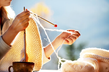 Close-up hands knitting white wool on knitting needles. handicrafts in nature.