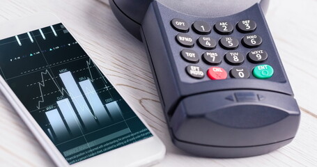 Image of financial data processing on smartphone next to credit card terminala