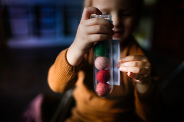 Cute european child on the floor playing with balls and probe, the child studies the color using the game. Sensory Development and Domestic Lessons, Dark Style in the Real Interior