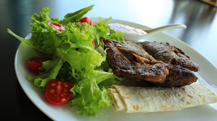 Fried Meat With Tomatoes And Vegetables On A White Plate  
