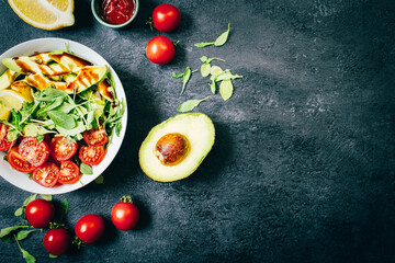 top view of tomato salad arugula avocado lemon in white plate on black background