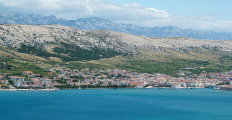Fototapeta na wymiar View over blue adriatic sea on village with dizzy mountains background - Island Pag, Croatia (focus on center of village)