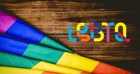 Lgbtq text and rainbow flag over wooden boards