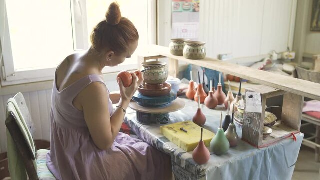 Beautiful woman painting handmade pottery at ceramic workshop