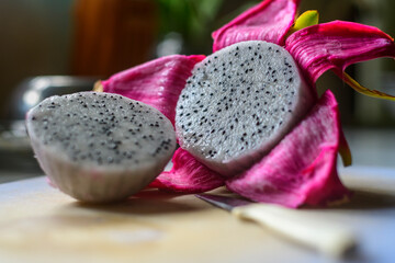 Two halves of Dragon fruit on a wooden cutting board with a small knife. peeled off and cut into two pieces in the home kitchen. Fresh fruit for making a delicious juice.