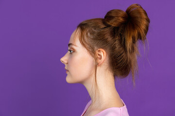 Side view. Portrait of young pretty girl isolated on purple, lilac color studio background. Concept of human emotions, facial expression, natural beauty, youth