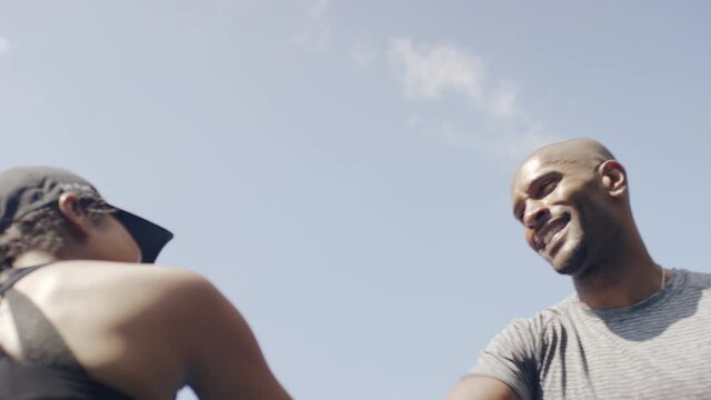 Male and female talking out in a park before giving a high five, in slow motion