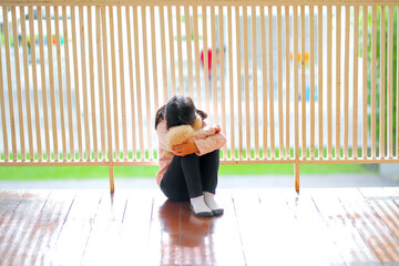 The little girl asian sitting in the house alone, have feelings depressed,  unhappy.