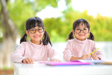 little girl two asian wearing glasses and doing homework together at home  which increases the development and enhances outside the classroom learning skills concept.