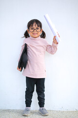 A little girl asia looks happy while celebrating his graduation and holding a diploma and graduation cap  which increases the development and enhances outside the classroom learning skills concept.