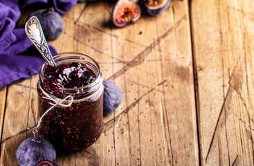 Fig confiture in glass jar. Fresh fruits on wooden kitchen table, negative space