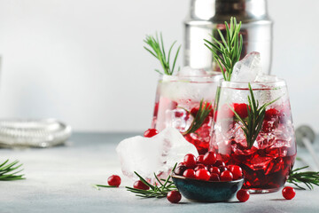 Winter Cranberry cocktail with vodka, ice, juice, rosemary and red berries. Festive long drink. Gray table background with negative space