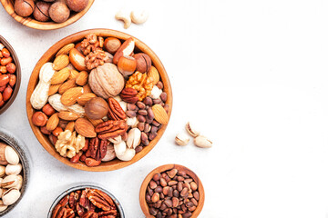 Nut mix in bowl. Almonds, hazelnuts, walnuts and other. Healthy food snack mix on white table, top view, copy space